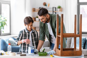 repair, diy and home improvement concept - father and son in protective gloves stirring grey color...