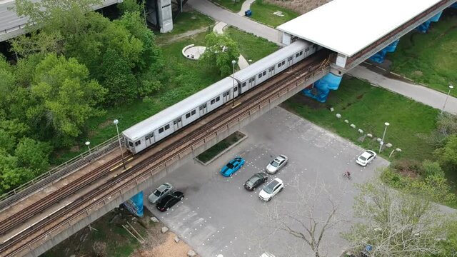 Subway train coming out of station over a bike path and parking lot