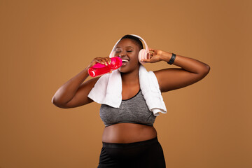 Young Black Woman Wearing Headphones Drinking Water At Studio