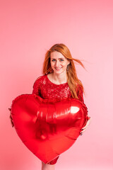 Beautiful redhead girl with red heart baloon posing. Happy Valentine's Day concept