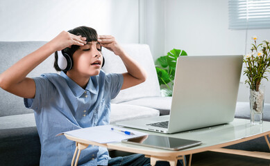 Young Serious Preteen child focused on online class's exam or quiz by using laptop. Mix race boy gets stress or bored during online exam in class. Teen Education for Self Learning Technology Concept