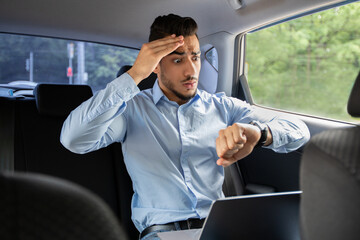 Worried arab businessman looking at watch while sitting in car
