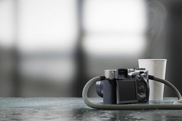 Camera and coffee cup placed on table with blurred background 3d rendering