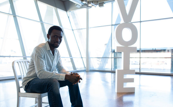 Portrait confident young man sitting near Vote text