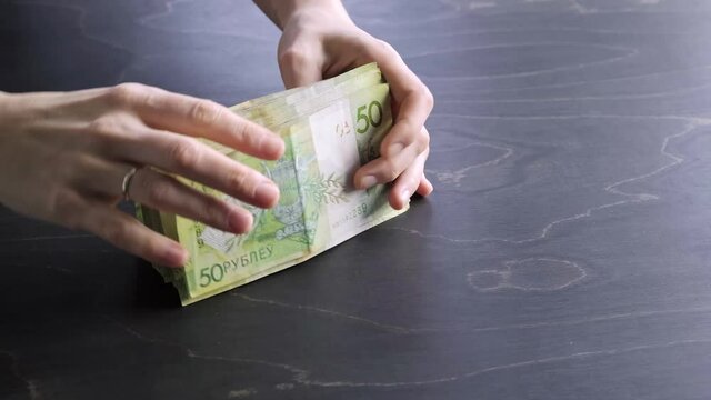4k. Close-up view of counting stack of belarusian 50 ruble paper money. Hands hold and count a lot of cash. Saving. National currency of Belarus. Credit liabilities. Profit. Big debt. Taxes payment.