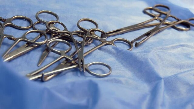 Group Of Surgical Clamps On Blue Medical Tissue