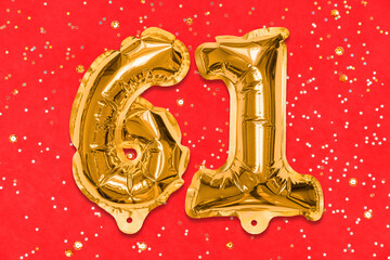 The number of the balloon made of golden foil, the number sixty-one on a red background with...