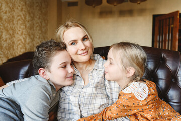 Smiling mother with daughter and son sitting on sofa at home