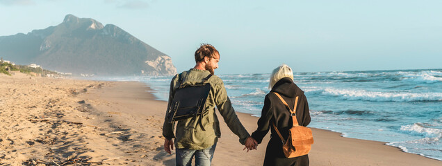 Horizontal banner with hipster young couple in love walking together at sunset along the desert...