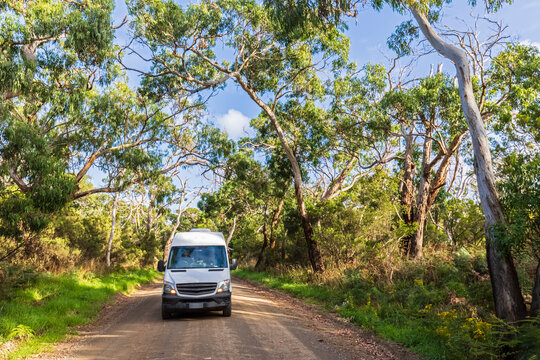 Van driving along dirt stretch of Great Ocean Road in summer - Powered by Adobe
