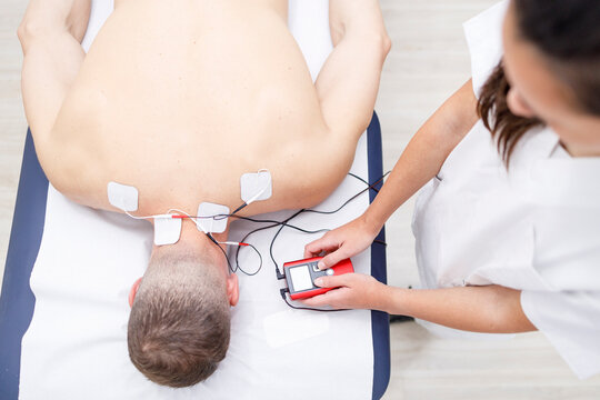 Physical therapist operating electrodes on athlete's neck