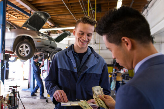 Customer paying mechanic with cash auto repair shop