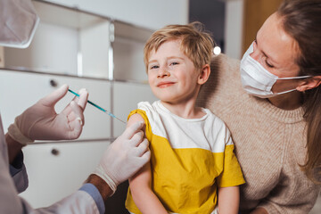 Smiling boy getting vaccine injection by doctor in center