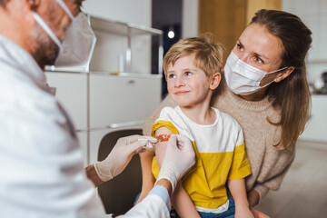 Doctor putting bandage on smiling boy's arm at center