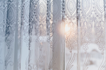 Close-up of patterned tulle on the window. Winter nature outside the window. Interior details.