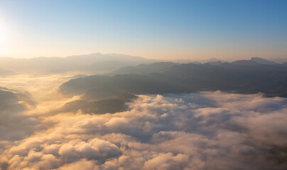 Fototapeta premium Aerial top view of forest trees and green mountain hills with sea fog, mist and clouds. Nature landscape background, Thailand.