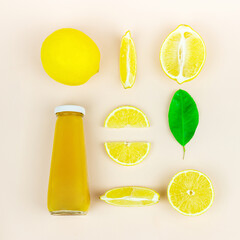 Top view of glass bottle of yellow juice surrounded with citrus fruits slices on pastel surface. Ingredients for summer drink and lemonade.