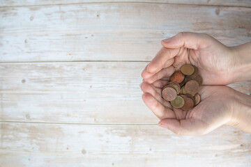 Hands holding pile of money euro coins in hand on wood background. Donation, saving, fundraising...