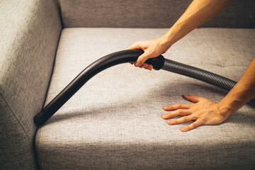 hand using vacuum cleaner on the sofa