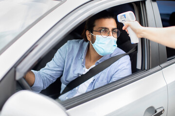 Middle-eastern man driver wearing protective face mask, getting temperature check-up