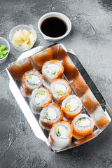 Variety of different sushi and rolls fro, salmon and tuna in delivery food concept, on gray stone background