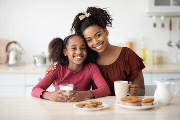 Loving black mother and daughter enjoying fresh cookies