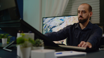 Photographer with disability doing retouch work on pictures for media production in workplace. Man working as editor retouching photos using touch screen monitor sitting in wheelchair