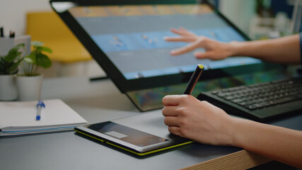 Close up of media specialist hands using graphic tablet with stylus and touch screen on monitor for...