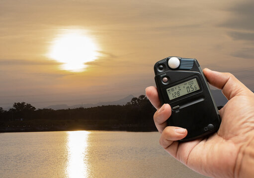 Photographers use light meters to measure correct exposure settings in landscapes at sunset.