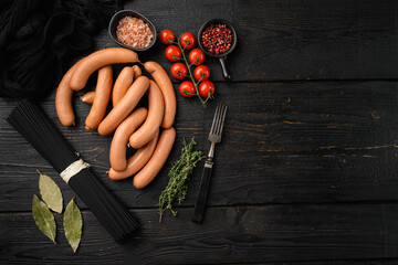 Raw frankfurter sausages, on black wooden table background, top view flat lay, with copy space for text