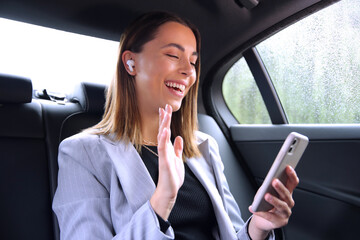 Businesswoman With Wireless Earbuds Commuting To Work In Taxi Making Video Call On Mobile Phone