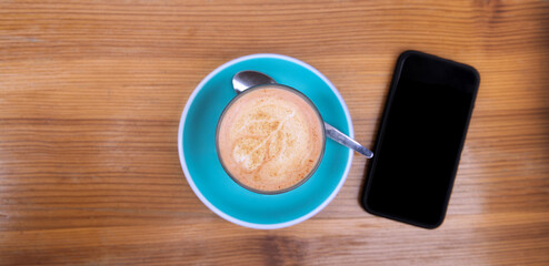 Close Up Of Cup Of Coffee And Mobile Phone On Wooden Table At Outdoor Café Or Coffee Shop