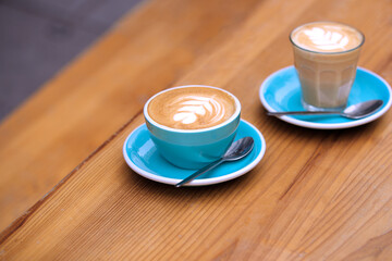 Close Up Of Two Cups Of Coffee On Wooden Table At Outdoor Café Or Coffee Shop