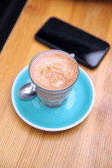 Close Up Of Cup Of Coffee And Mobile Phone On Wooden Table At Outdoor Café Or Coffee Shop