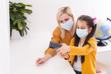 mother and little daughter take a selfie in masks