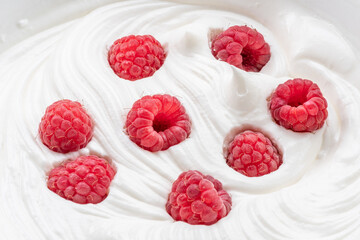 Fresh raspberries in the yoghurt or cream. Top view.