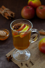 apple cider with fresh apples and honey. Hot fruit tea with spices: cinnamon, cardamon, anise, clove on the wooden table. Christmas drinks with sackcloth. mulled wine. vertical