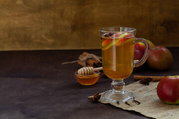 mulled wine with spices and apples. homemade apple cider with fresh apples, honey, cinnamon, cardamon, anise, clove. hot fruit tea on the wooden table. Christmas drinks with sackcloth. cope space.