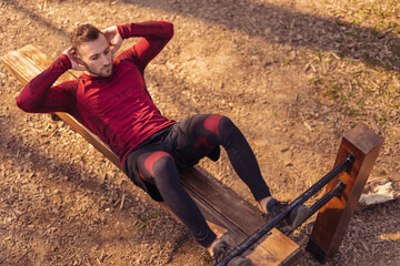 Active man doing crunches in street workout park