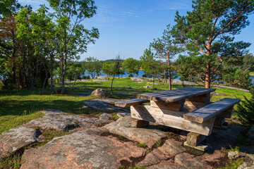 Wooden picnic table and beautiful landscape with ocean view along the nature trail at the Höckböleholmen nature reserve in Åland Islands, Finland, on a sunny day in the summer.