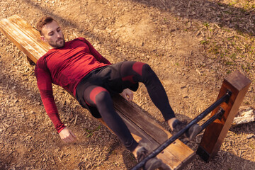Active man doing sit ups in street workout park