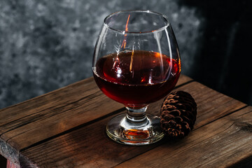 A glass of cognac on a dark background. Cognac on a wooden background. Alcohol on a wooden table. French cognac.
