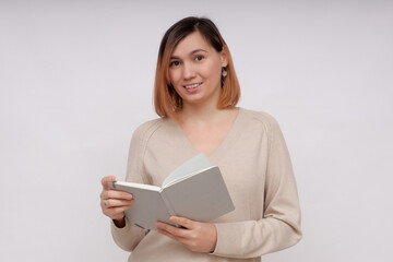 Fototapeta premium Beautiful girl holding a book standing on a white background