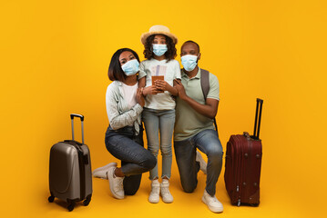 Safe travels. African american family wearing medical masks, posing with suitcases and passports...