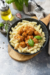 Italian  kitchen. Italian fusilli pasta with meat balls in tomato sauce and basil on grey stone background. Copy space.