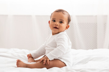 African American Infant Baby Sitting In Bed Smiling At Home