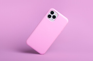 iPhone 11 and 12 pro max in pink silicone case falls down back view, phone case mockup isolated on pink background