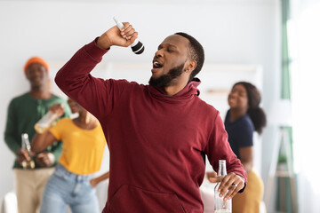 Positive black guy with bottle of beer singing karaoke