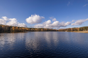 Sunny autumn in the park. Autumn landscape with colorful yellow, orange and red trees and reflection in the pond.