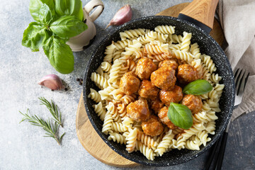 Italian  kitchen. Italian fusilli pasta with meat balls in tomato sauce and basil on grey stone background. Flat lay, top view.
